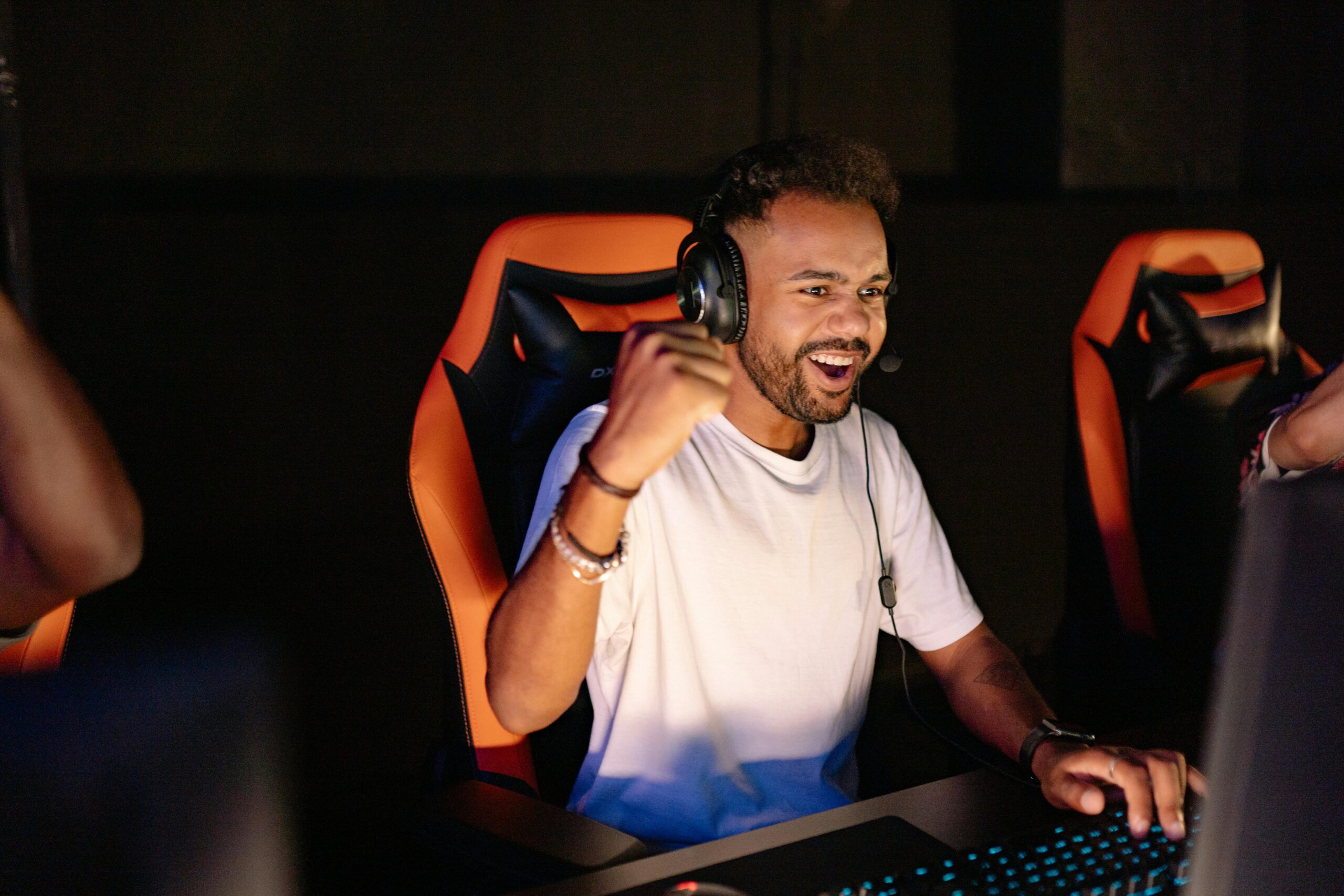 pexels photo 9072280 9072280 A man celebrating a win in a gaming chair, wearing headphones and using a PC.